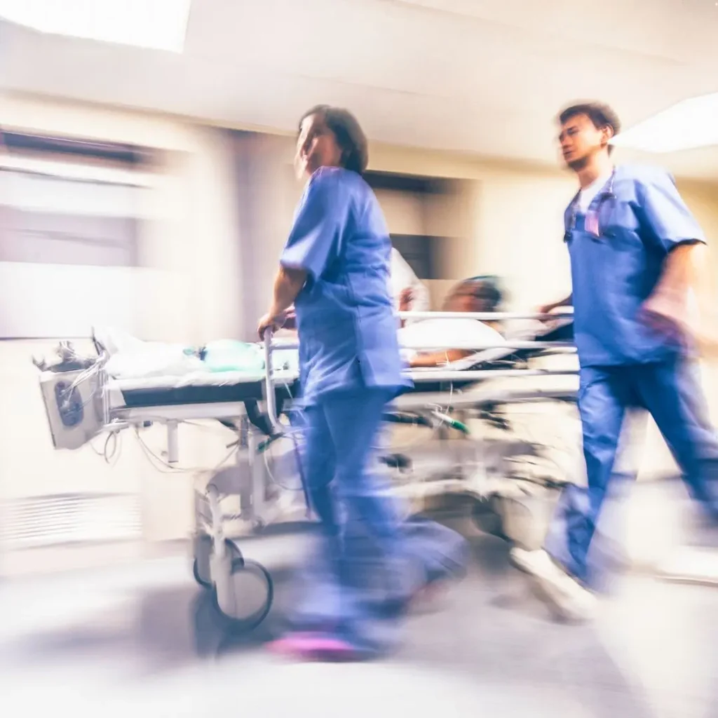 Equipe de enfermagem conduz maca em corredor de hospital